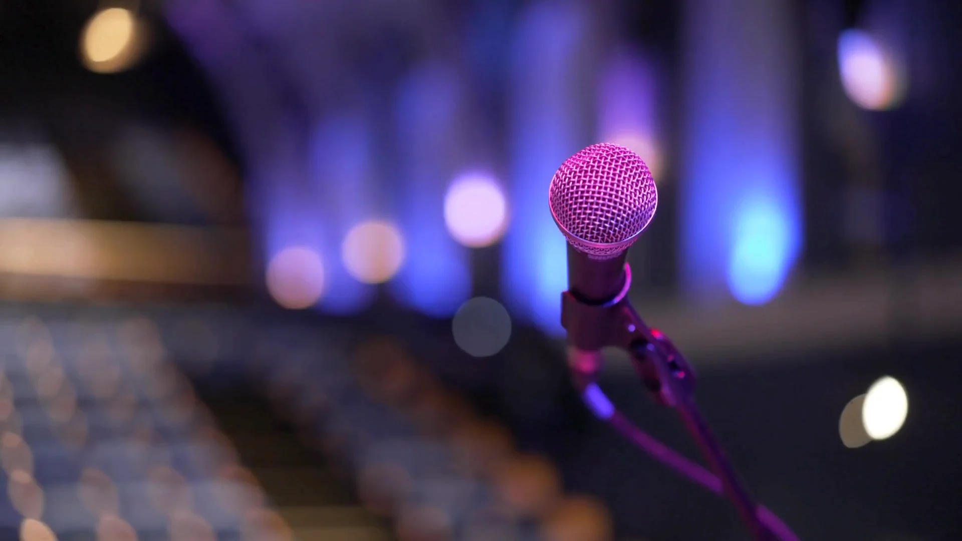 A stage microphone under concert lights.